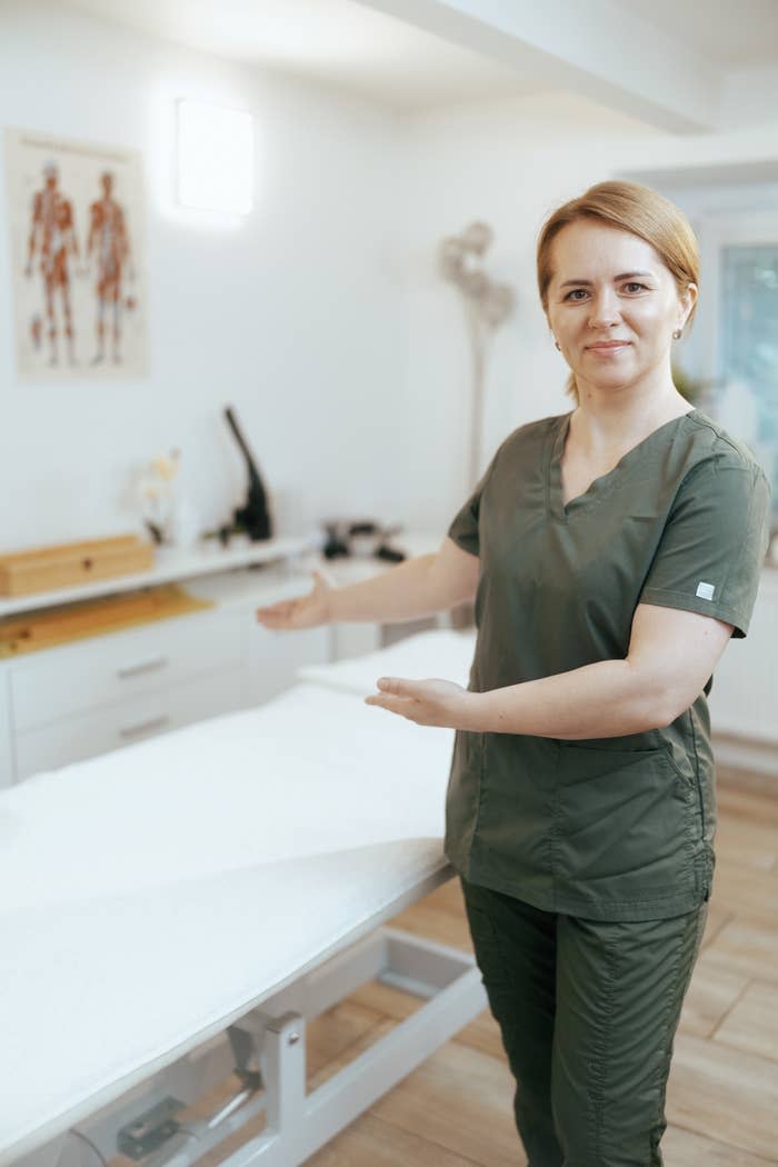 massage therapist motioning for client to lay on massage table